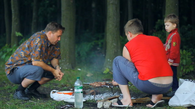 men cook the meat on the barbecue