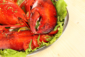 Red lobster on platter with vegetables on wooden table close-up