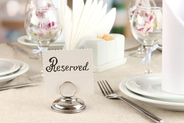 Reserved sign on restaurant table with empty dishes and glasses
