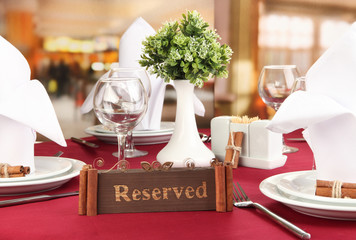 Reserved sign on restaurant table with empty dishes and glasses