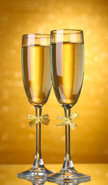 Two glasses of champagne on bright background with lights
