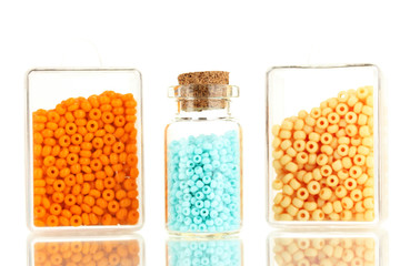 Colorful beads heap in boxes and glass bottle isolated on white