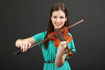 Beautiful young girl with violin on grey background