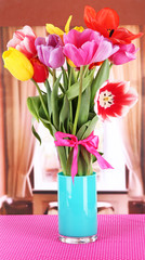 Beautiful tulips in bouquet on table in room