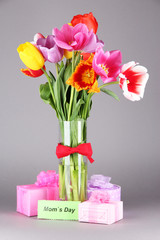 Beautiful tulips in bouquet with gifts and note