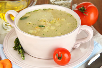 Nourishing soup in pink pan on wooden table close-up