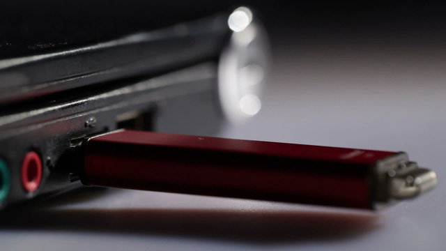 Inserting red usb flash drive in notebook. Macro shot.