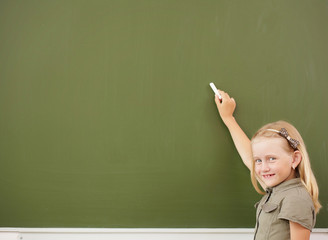 Scoolgirl standing near blackboard