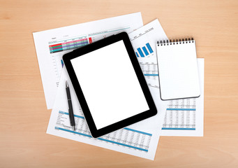 Tablet with blank screen over papers with numbers and charts
