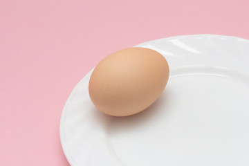 fresh eggs on a plate on pink background