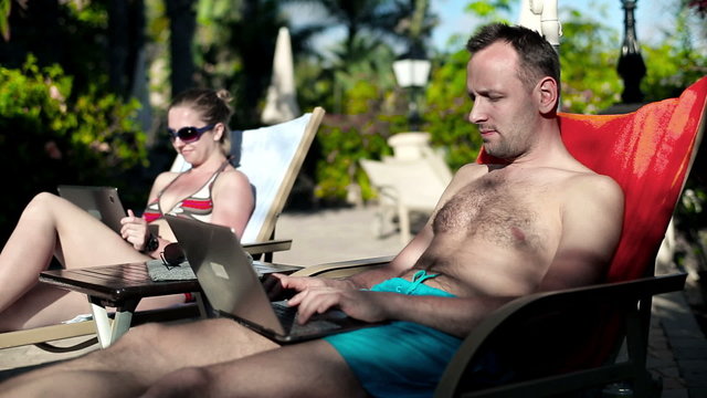 Young couple lying on sunbed using technology