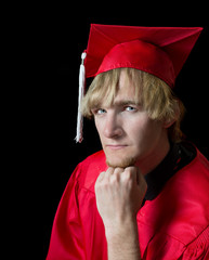 Handsome high school graduate wearing red cap and gown