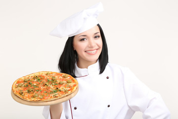 Beautiful girl chief-cooker with pizza isolated on white