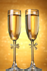 Two glasses of champagne on bright background with lights