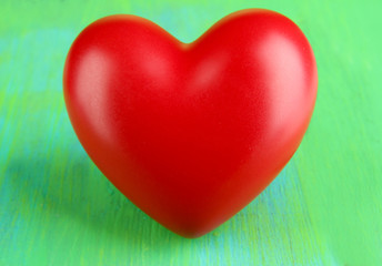 Decorative red heart on color wooden background