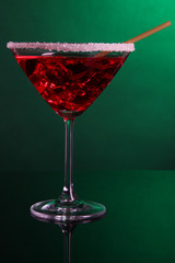 Red cocktail in martini glass on dark green background
