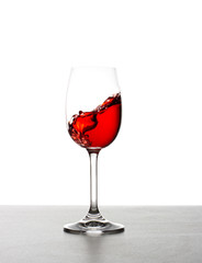 Red wine splashing from glass, isolated on white background