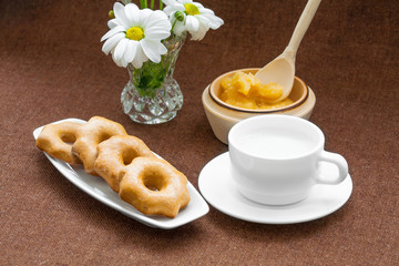 honey cookies, cup and a vase of daisies