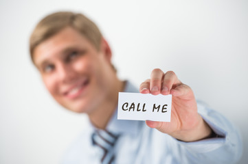 Handsome businessman showing "call me" text on a business card
