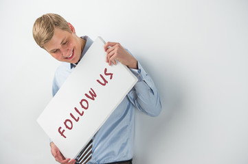 Handsome businessman showing "follow us" text on a billboard