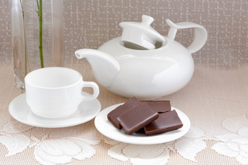 teapot, cup and chocolate on a plate