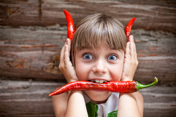 Girl with a red hot chili pepper in her mouth show devil horns