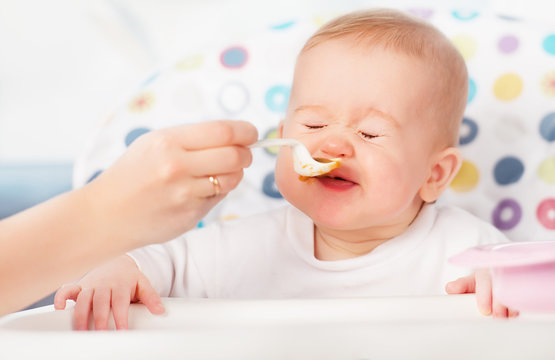 Mom feeds funny baby from  spoon