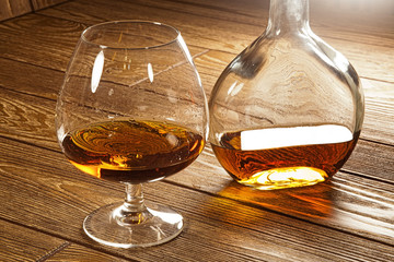 a glass of brandy and a bottle on a brown table
