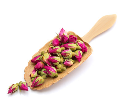 tea rose flowers in a wooden spoon isolated on white