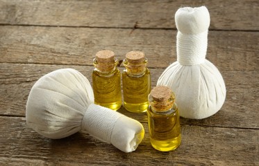 Massageöl mit Kräuterstempel auf verwittertem Holz