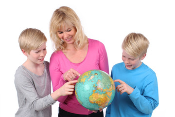 Mutter sucht mit Kindern Reiseziel auf dem Globus