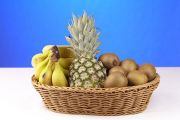 Korb mit Bananen, Ananas und Kiwis