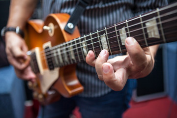 Fototapeta na wymiar Młody mężczyzna gra na gitarze w sali prób