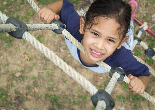 A cute girl is climbing on the rope ladder