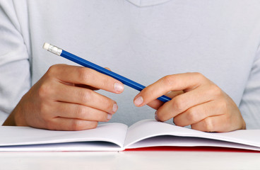 Manos sujetando un lápiz,pensando,escribiendo.
