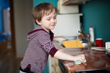 Fototapeta na wymiar Boy cleaning the kitchen
