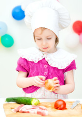 Little girl in chief hat cooking dinner