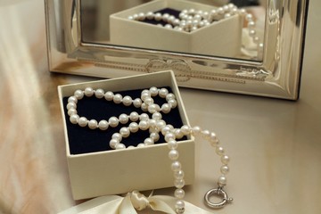 Pearl necklace in a gift box in front of a mirror