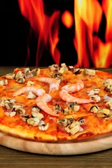 Foto op Plexiglas Delicious pizza with seafood on stand on flame background © Africa Studio
