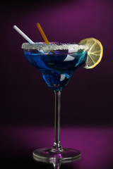 Blue cocktail in glass on color background