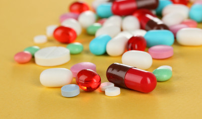 Assortment of pills, tablets and capsules on yellow background