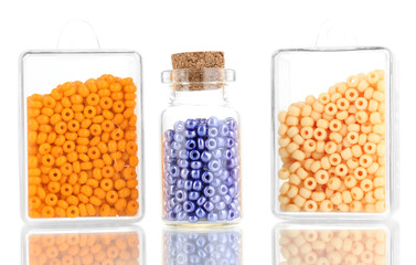 Colorful beads heap in boxes and glass bottle isolated on white