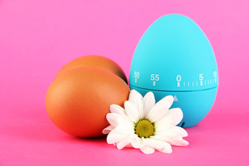 Blue egg timer and eggs, on color background