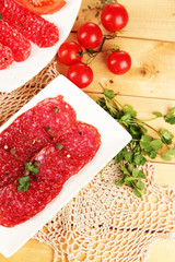Tasty salami on plates on wooden table close-up