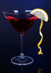 Red cocktail in martini glass on dark blue background
