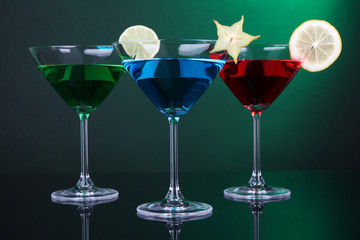 Alcoholic cocktails in martini glasses on dark green background