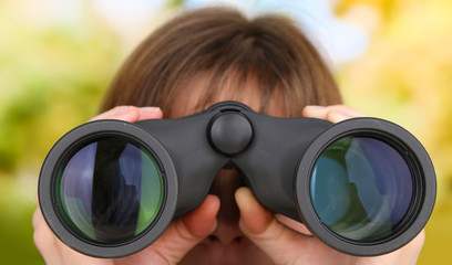 Black modern binoculars in hands on green background