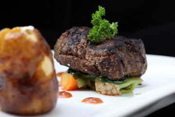 Tenderloin steak portion with potato on black background