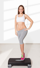 Young beautiful woman doing exercises with aerobic step