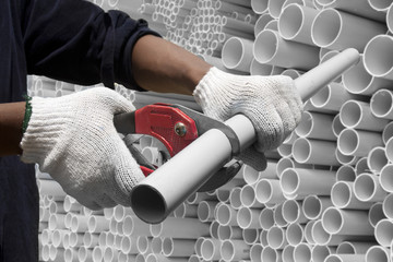Worker cutting pvc pipe in construction site - obrazy, fototapety, plakaty